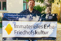 Mike Raptis beim Aufhängen des Banners auf dem Friedhof Dorotheenstadt I (© EvFBS)